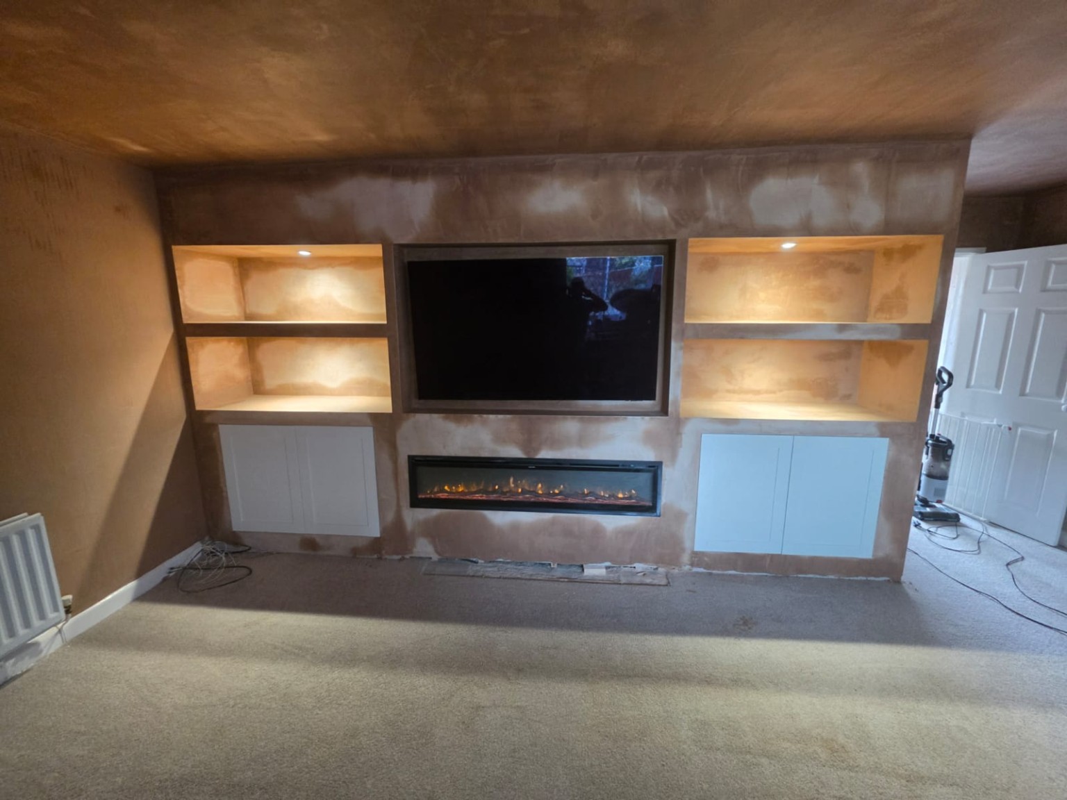CS Plastering bespoke media wall with illuminated shelves, electric fire and base cabinets